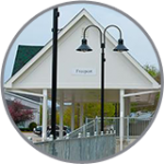 White pavilion with a "Freeport" sign, near black street lamps, under cloudy skies—close to Freeport Maine Inns.