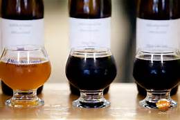 Three beer glasses sit by labeled bottles—a cozy scene after a day exploring things to do in Freeport Maine.