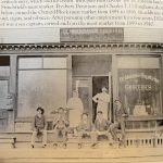 Black-and-white photo of seven people posed outside Dennison & Dillingham Meat Market and Groceries storefront.